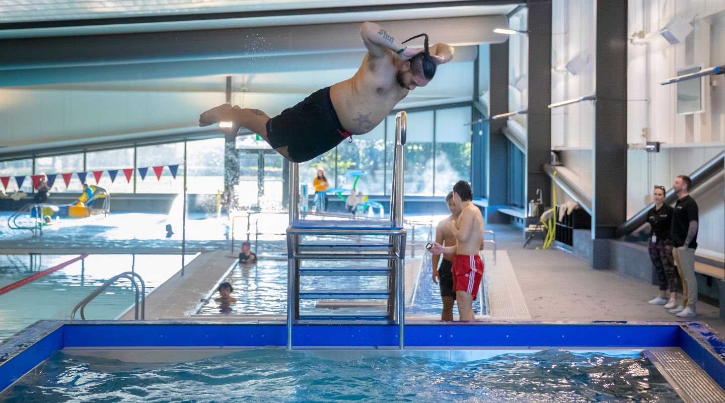 A man doing a belly flop off a diving board at Christchurch Recreation and Sport summer pool. 