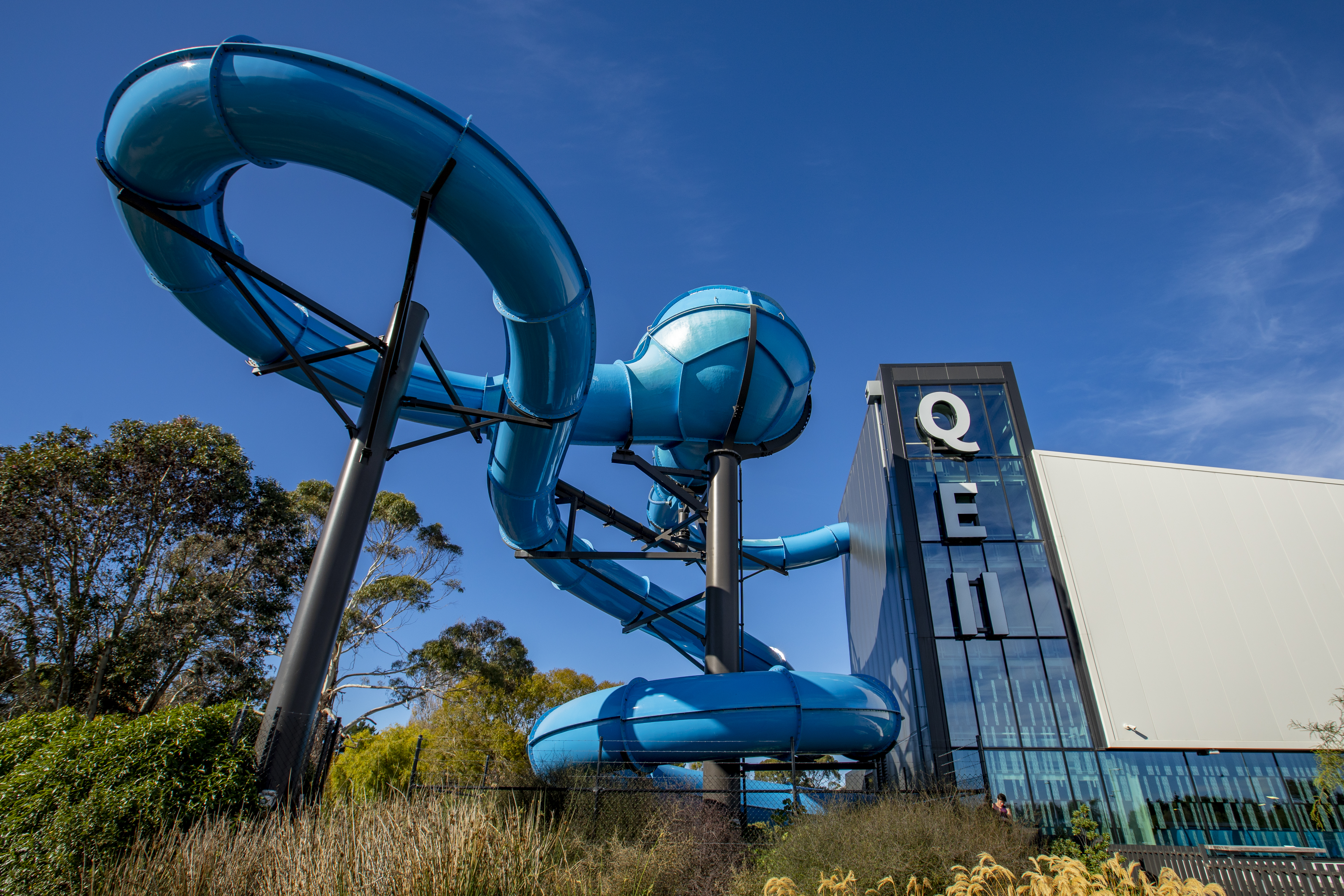 The outside of Taiora QEII Recreation and Sport centre with the blue hydroslide wrapping around the side. 