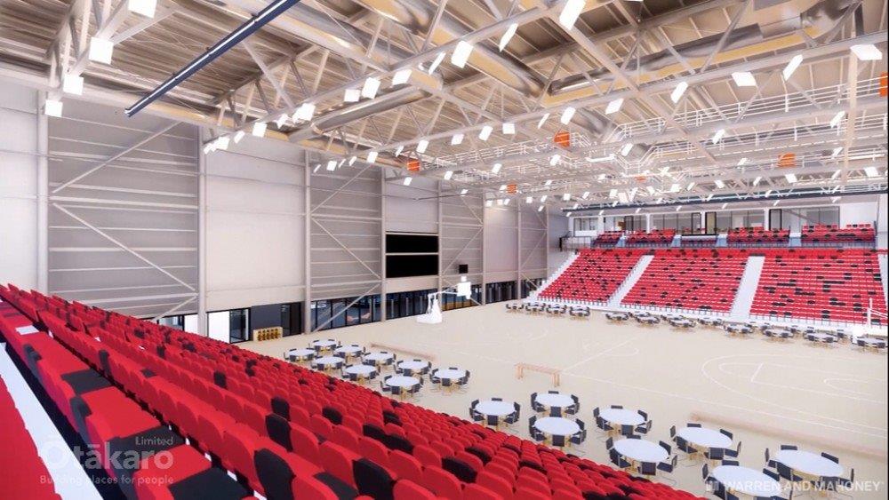 A concept design render of the interior sports court with red and black seating at Parakiore Recreation and Sport Centre. 