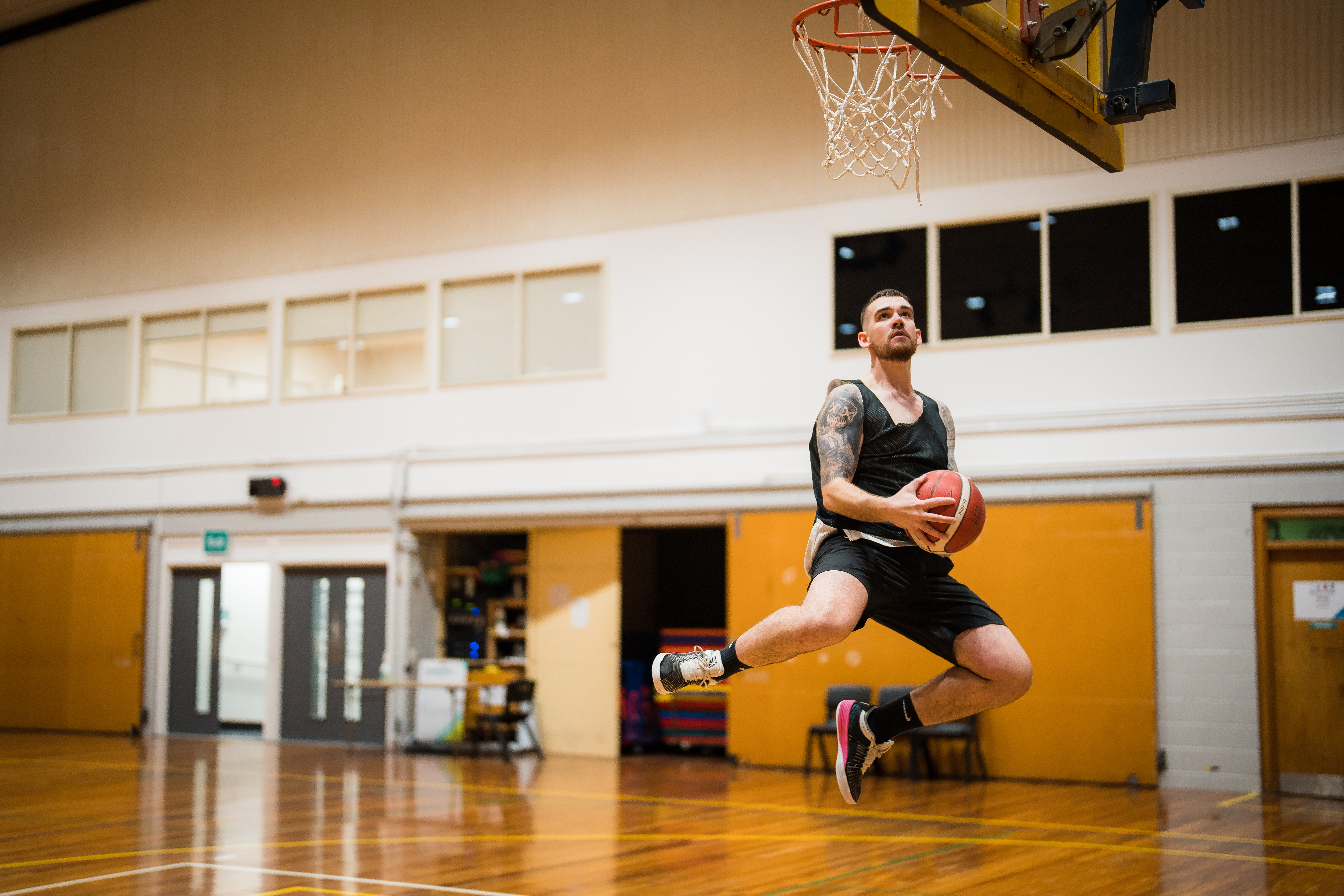 A man jumping and taking a shot into a basketball net at Christchurch Recreation and Sport. 