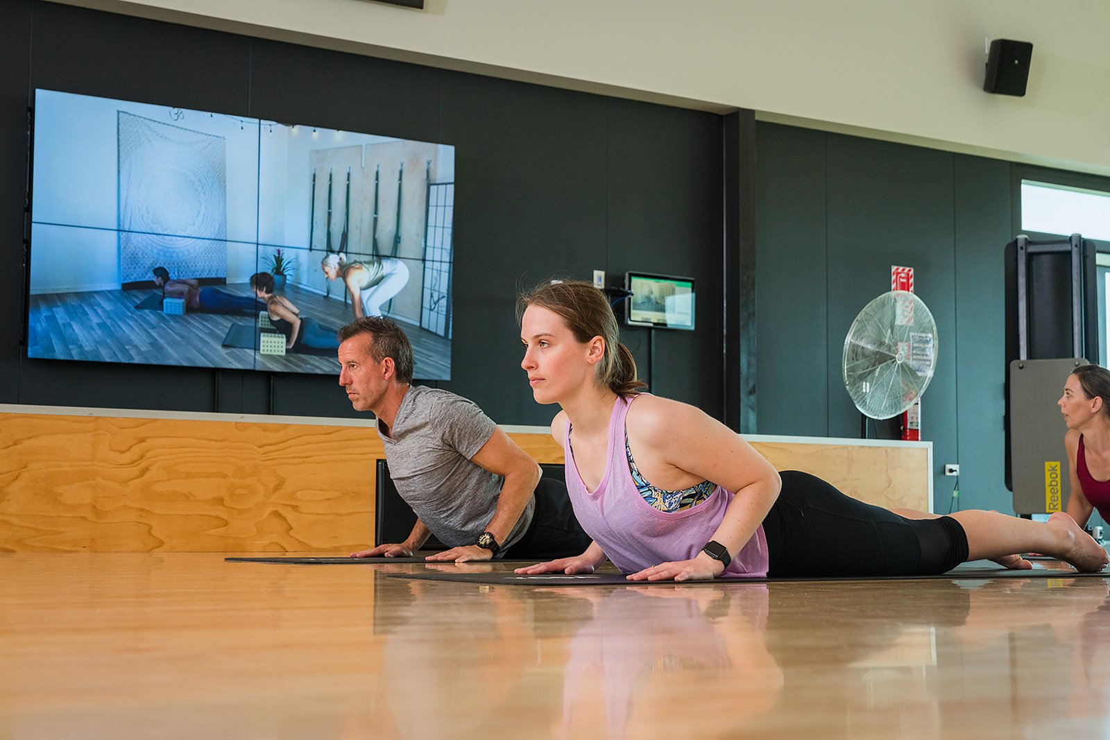 A man and a woman participating in a yoga class at Taiora QEII Recreation and Sport pool. 