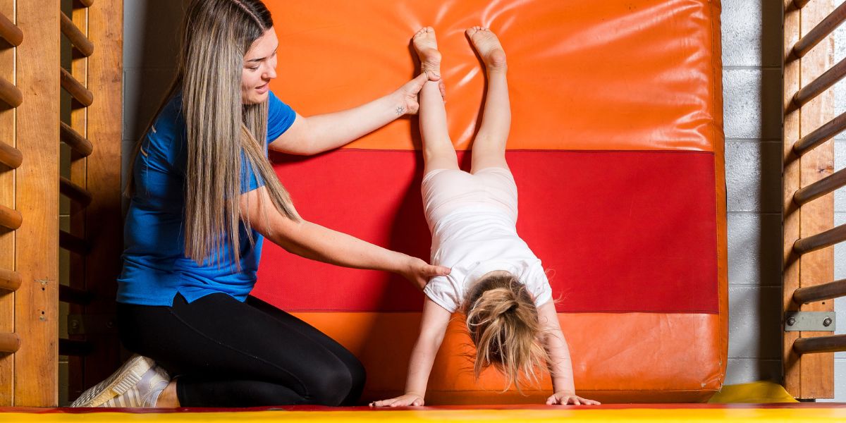 An instructor helping a child with a handstand during a pre-school gymnastics class at Christchurch Recreation and Sport centre. 