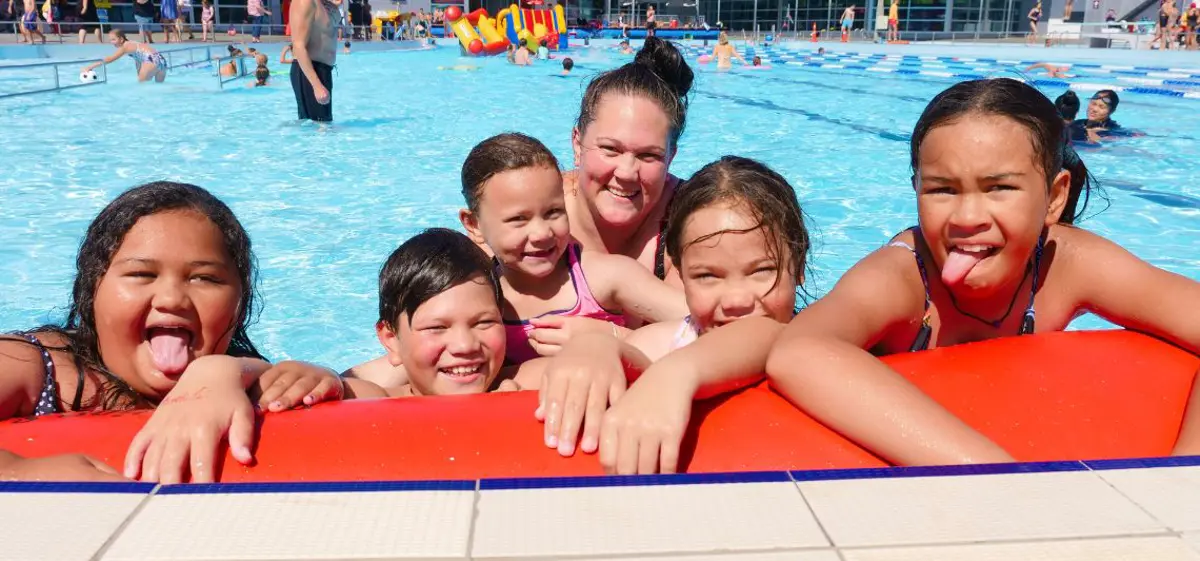 A group of smiling children holding onto an inflatable at Waltham Summer pool.