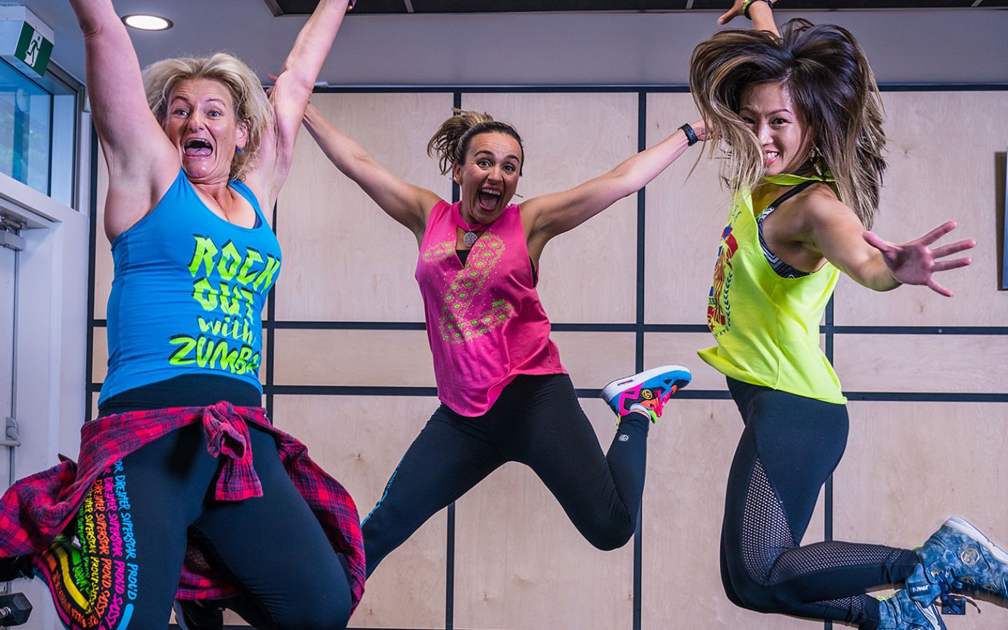 Three women in brightly dressed active wear jumping during a Zumba class at Christchurch Recreation and Sport.