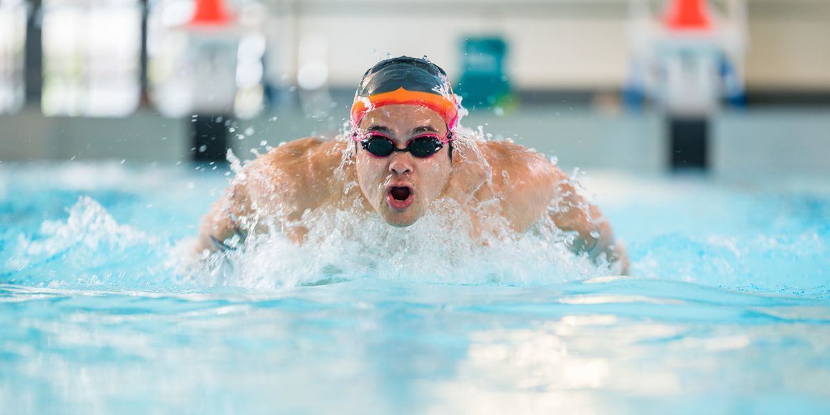 A man in the Matatiki lane pool wearing goggles and a swim cap doing a butterfly stroke. 