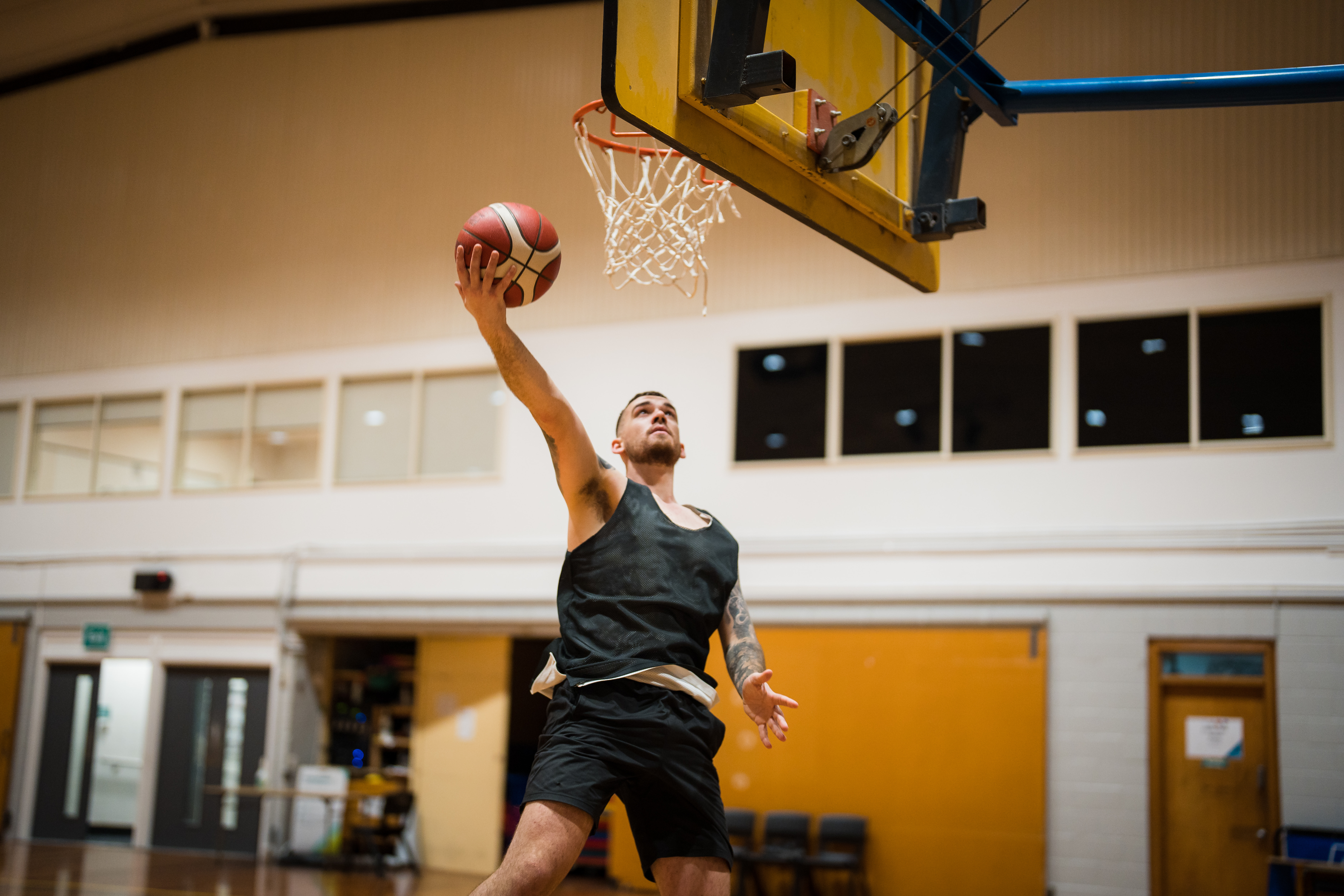 A man jumping and taking a shot into a basketball net at Christchurch Recreation and Sport. 