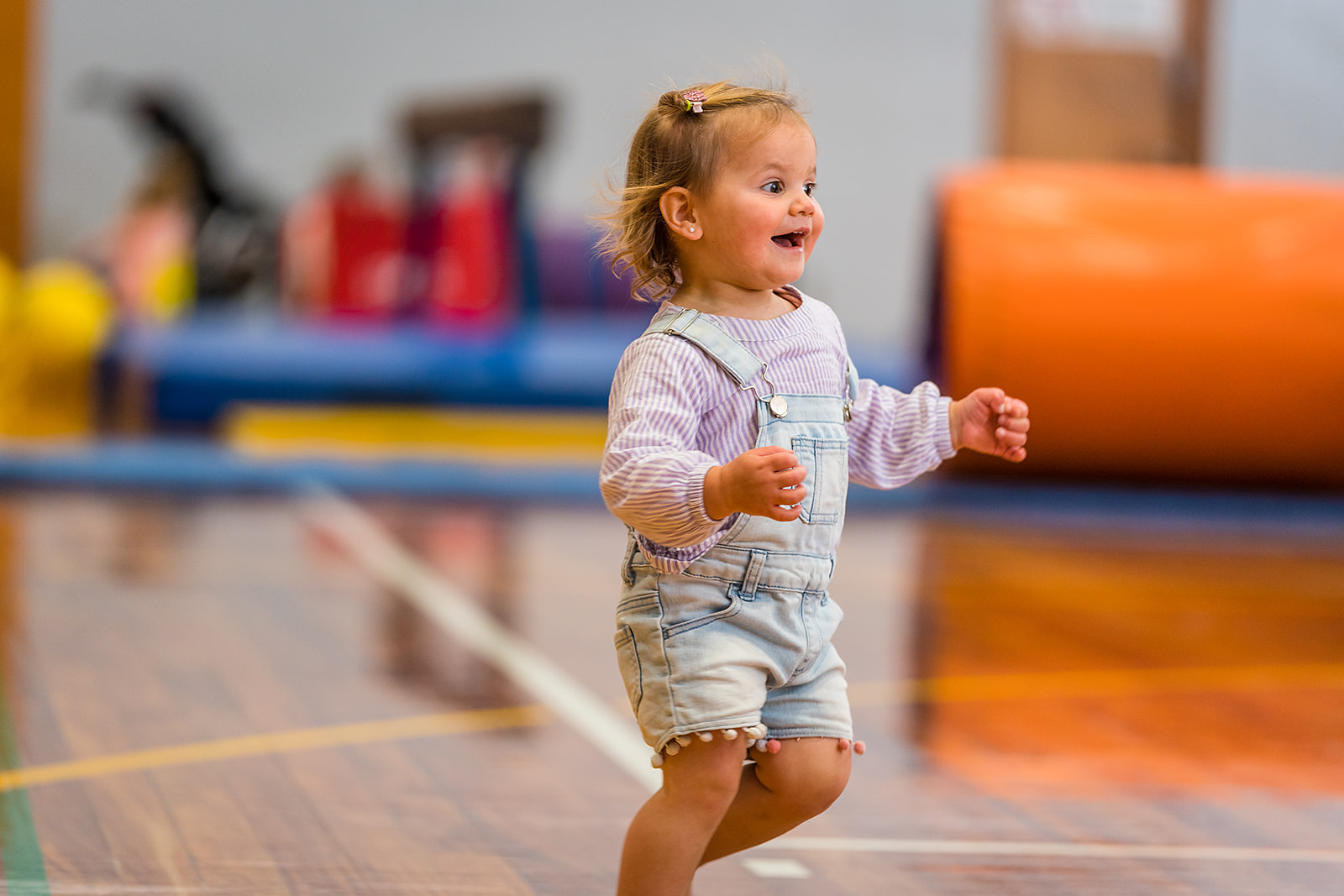 A smiling toddler running during a Tumbletimes class at Christchurch Recreation and Sport Centre.