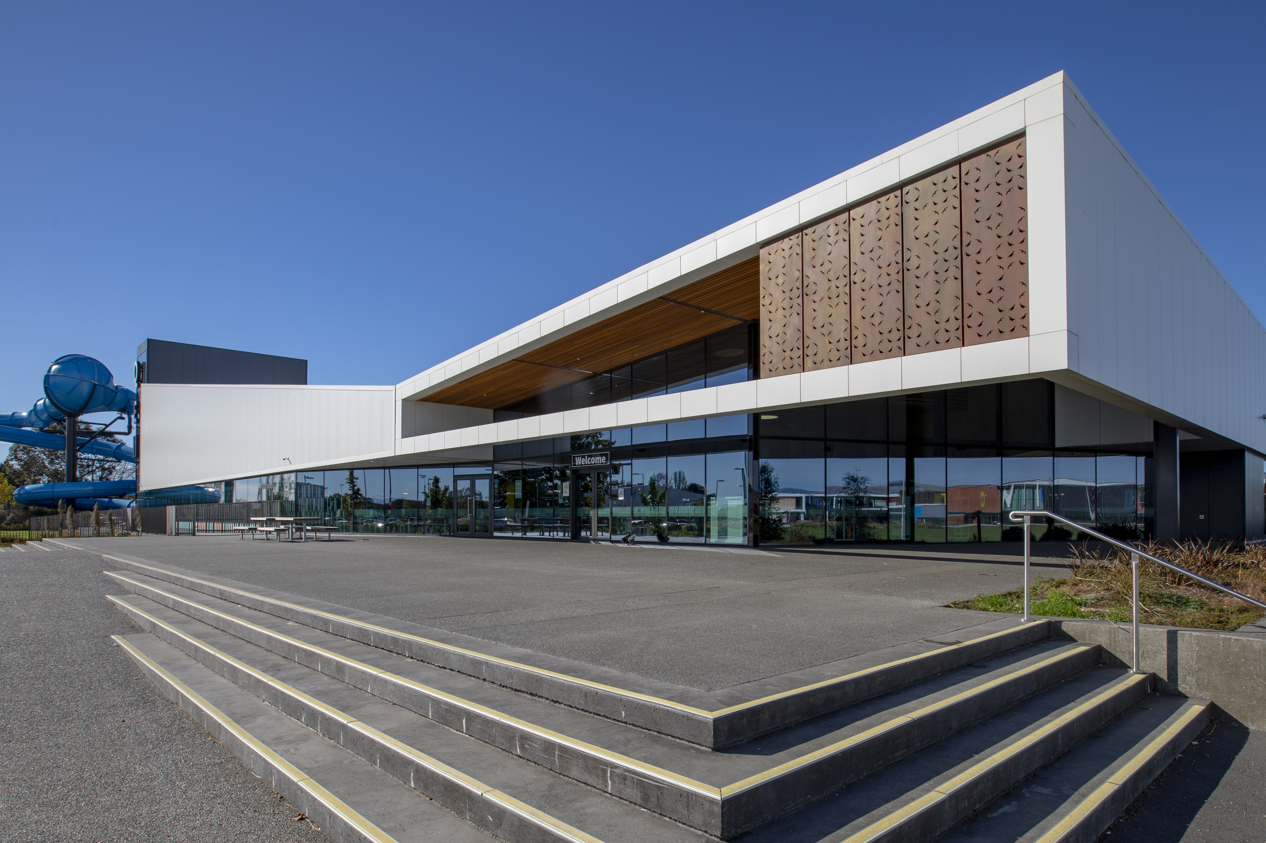 The outside of Taiora QEII Recreation and Sport centre with the blue hydroslide wrapping around the side. 