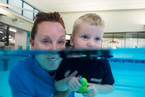 A little boy and a female swim instructor practicing holding their breath at Christchurch Recreation and Sport pool. 