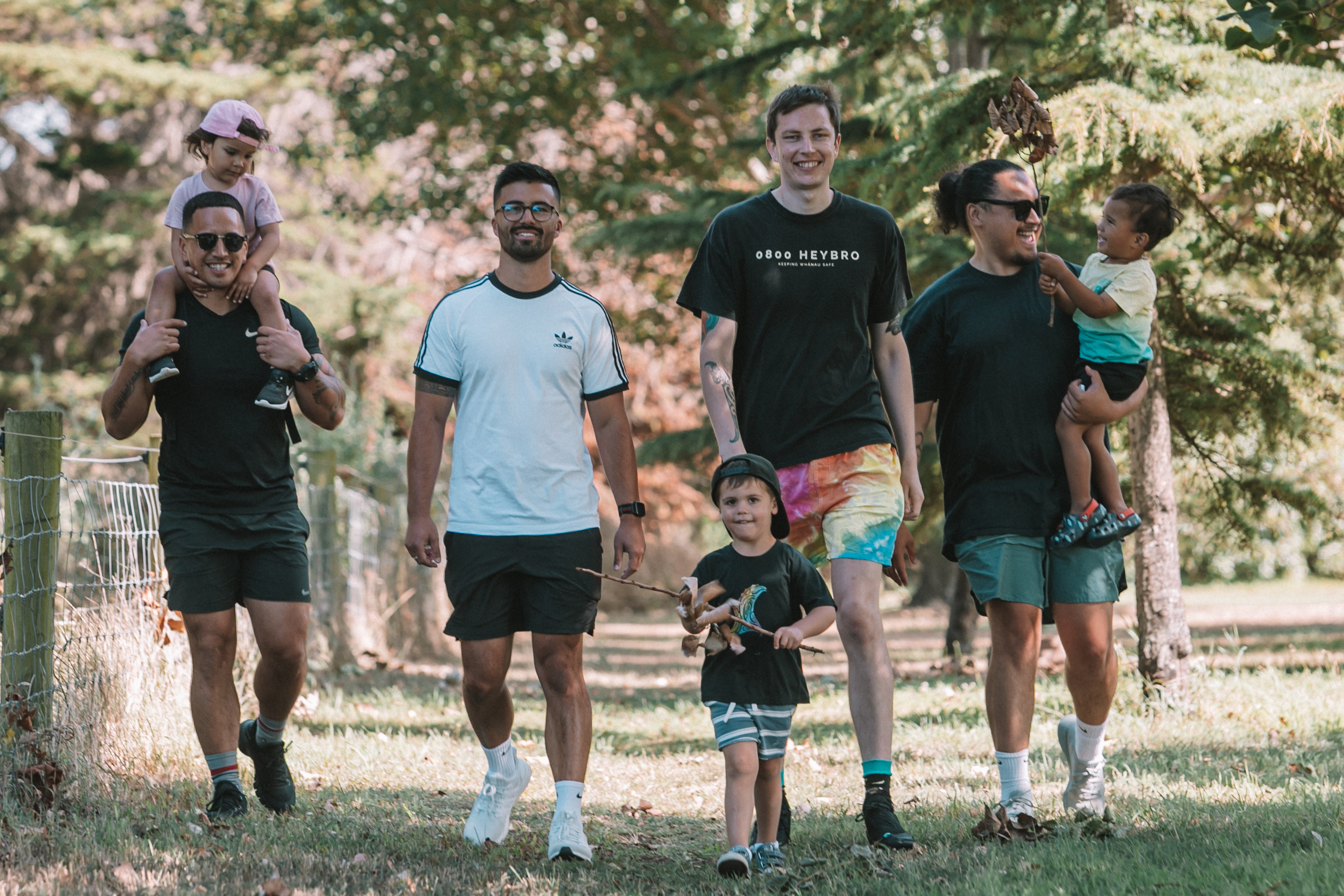 Three men walking with a group of young children outside. 